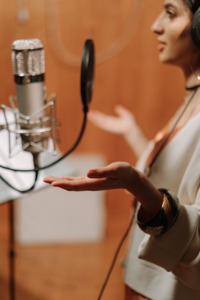 A female singer recording vocals in a professional music studio with a microphone.