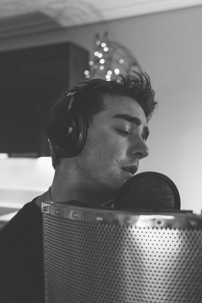 Black and white portrait of a male singer recording in a music studio.